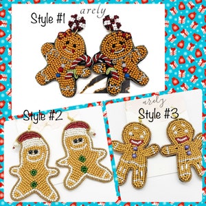 May include: Three pairs of gingerbread man earrings. The first pair has a red and white candy cane and a red hat. The second pair has a white Santa hat with a pearl. The third pair has a simple gingerbread man design.