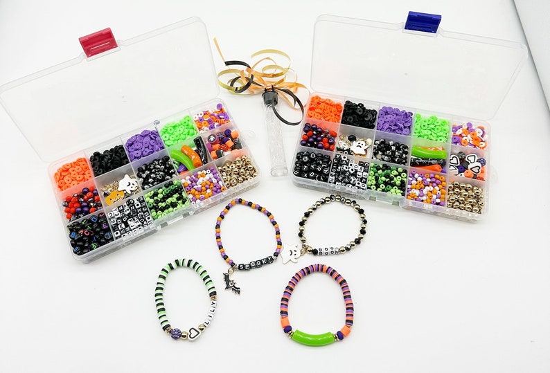 May include: Two clear plastic containers filled with various Halloween-themed beads, including black, white, orange, green, and purple beads. Four bracelets made with the beads are shown below the containers.