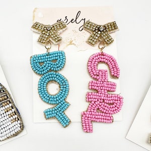 May include: A pair of beaded earrings with gold bows. One earring says "BOY" in blue beads and the other says "GIRL" in pink beads.