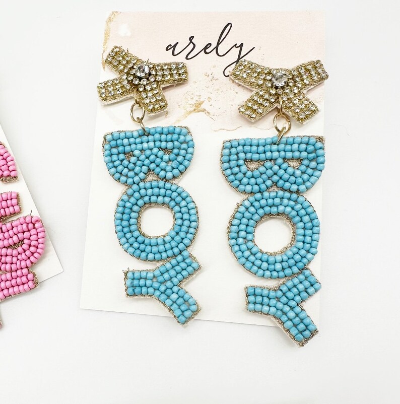 May include: A pair of blue beaded earrings with gold accents and a rhinestone bow. The earrings spell out the word "BOHO".