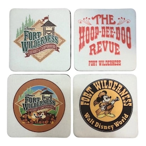 May include: Set of four square coasters featuring Disney's Fort Wilderness Resort & Campground and The Hoop-Dee-Doo Revue. Designs include logos and images of Mickey Mouse. The coasters are white with various colors.