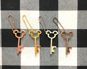 May include: Four key-shaped bottle openers with Mickey Mouse head cutouts. The openers are gold, silver, rose gold, and copper.