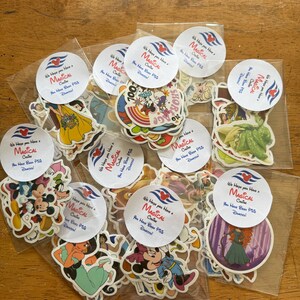 May include: A collection of assorted character stickers packaged in clear plastic bags, each sealed with a round white label featuring a red and blue cruise ship logo and the text We Hope You Have a Magical Cruise You Have Been Pixie Dusted.