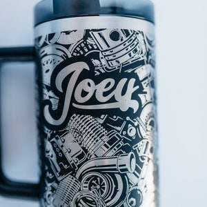 May include: Stainless steel tumbler with a black handle and lid. The tumbler features a detailed graphic design of engine parts and the name "Joey" in a stylized font. Includes a gray straw.
