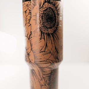 Pu&ograve; includere: Un bicchiere in acciaio inossidabile con coperchio e cannuccia neri. Il bicchiere &egrave; decorato con un dettagliato motivo a girasole marrone e nero. Il motivo floreale avvolge l'intero corpo del bicchiere.
