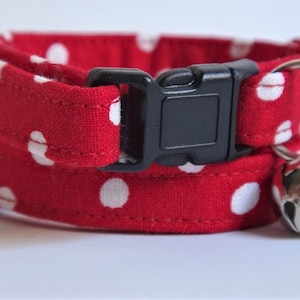 May include: Red and white polka dot cat collar with a black plastic buckle and a silver bell.