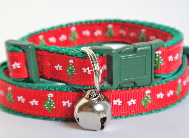 May include: Red and green cat collar with a Christmas tree pattern and a silver bell.