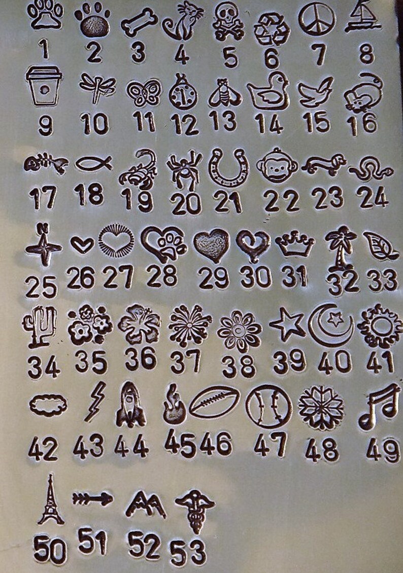 May include: A metal sheet with various small, engraved designs and corresponding numbers. The designs include paw prints, a bone, a cat, a skull, a coffee cup, a dragonfly, a butterfly, a bee, a duck, and more.