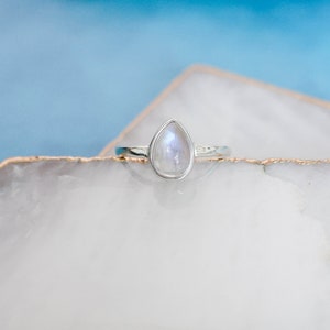 May include: A silver ring with a teardrop-shaped moonstone.