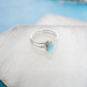 May include: A silver ring with a teardrop-shaped blue gemstone.