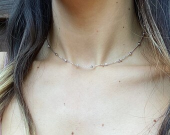 May include: A silver chain necklace with small round beads. The necklace is delicate and simple.