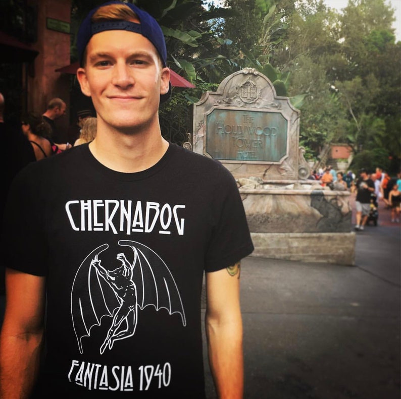 Puede incluir: Una persona lleva una camiseta negra con un gr&aacute;fico blanco de una criatura con alas. El texto "Chernabog Fantasia 1940" est&aacute; impreso en la camiseta.
