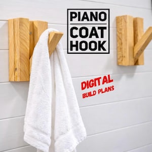 May include: Wooden coat hooks with a natural finish are mounted on a white wall. A white towel hangs from one hook. The text "PIANO COAT HOOK" and "DIGITAL BUILD PLANS" are visible.