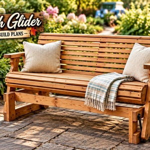 May include: A wooden bench glider featuring horizontal slats, two beige throw pillows, and a plaid throw blanket. A sign above reads Bench Glider DIGITAL BUILD PLANS. The bench is positioned on a stone patio with autumn decor nearby.