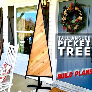 May include: A tall, angled picket tree made of light-colored wood with a black metal frame. The tree is displayed on a porch with a wreath on the door. Text on the image reads "TALL ANGLED PICKET TREE" and "BUILD PLANS".