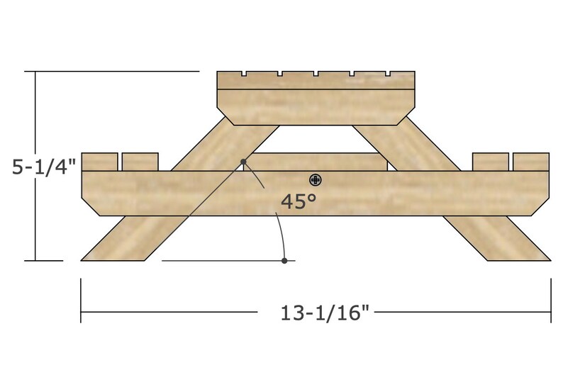 May include: Line drawing of a wooden picnic table with dimensions 13-1/16 inches wide and 5-1/4 inches high. The table top is made of two pieces of wood joined together. The legs are angled at 45 degrees.