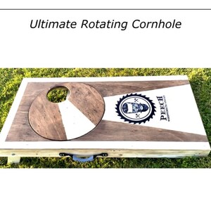 May include: A wooden rotating cornhole game with a white and brown target and a black and white logo that says "Peech Woodworking Co."