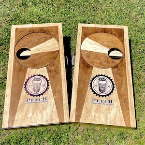 May include: Two wooden cornhole boards with a circular target and a skull logo. The logo says "Peech Woodworking and DIY".