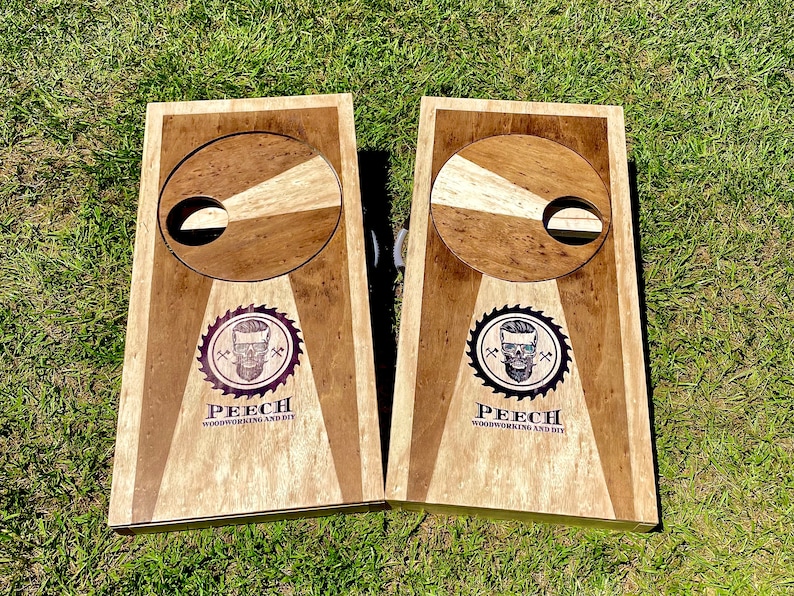 May include: Two wooden cornhole boards with a circular target and a skull logo. The logo says "Peech Woodworking and DIY".