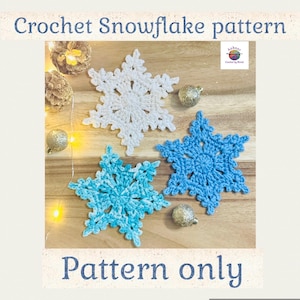 Op de afbeelding: Drie gehaakte sneeuwvlokpatronen in wit, lichtblauw en blauw, met de tekst "Crochet Snowflake pattern" en "Pattern only". De sneeuwvlokken worden gepresenteerd op een houten oppervlak met decoratieve gouden ornamenten.