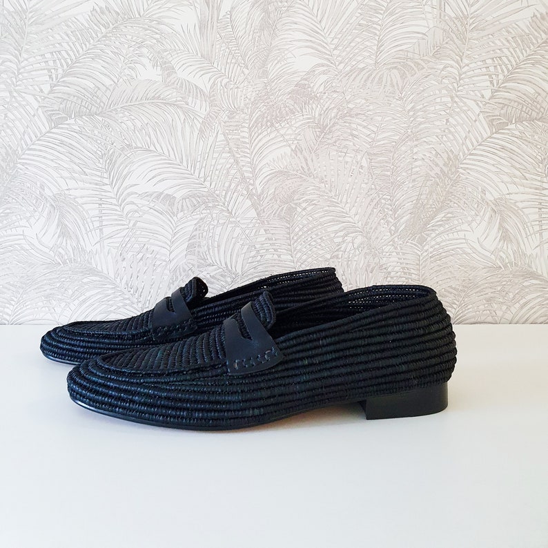 Puede incluir: Un par de mocasines de cuero negro tejido. Los mocasines tienen un dise&ntilde;o sencillo con una sola correa en la parte superior.