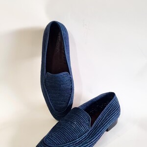 May include: A pair of blue woven leather loafers. The loafers have a pointed toe and a flat sole.