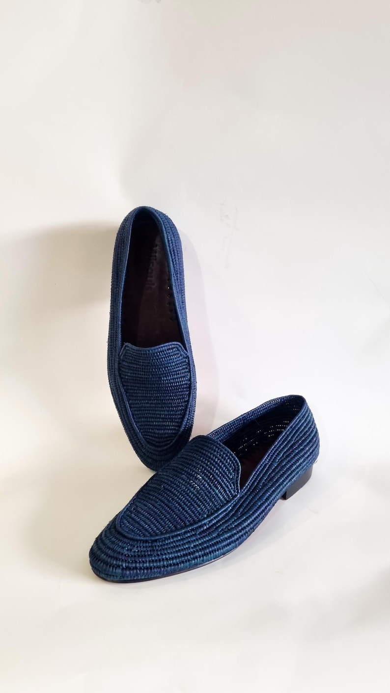 May include: A pair of blue woven leather loafers. The loafers have a pointed toe and a flat sole.