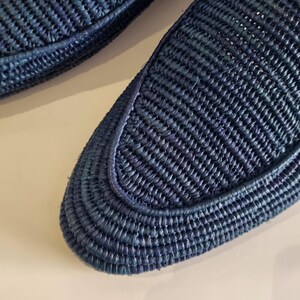 May include: A pair of blue woven leather loafers. The loafers have a woven texture and a pointed toe.