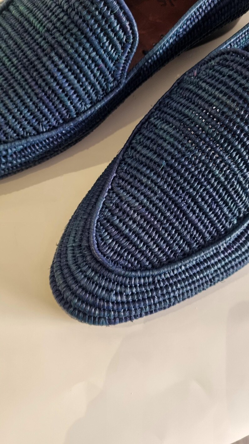 May include: A pair of blue woven leather loafers. The loafers have a woven texture and a pointed toe.
