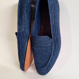 May include: A pair of blue woven leather loafers. The loafers are made from a woven material and have a pointed toe.