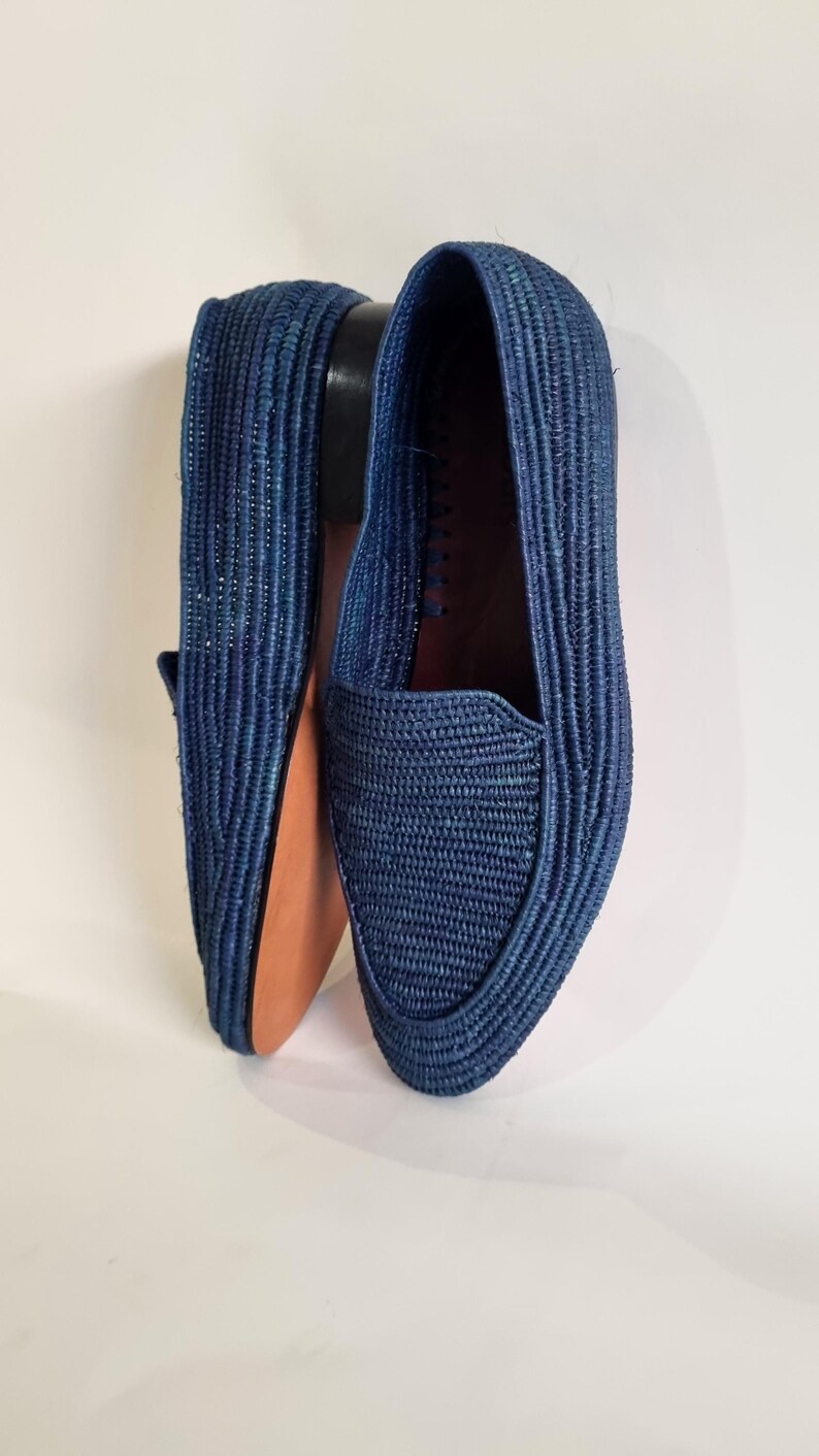 May include: A pair of blue woven leather loafers. The loafers are made from a woven material and have a pointed toe.
