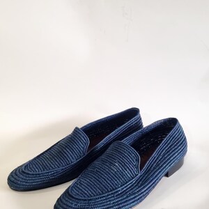 May include: A pair of blue woven leather loafers. The loafers have a pointed toe and a woven upper.