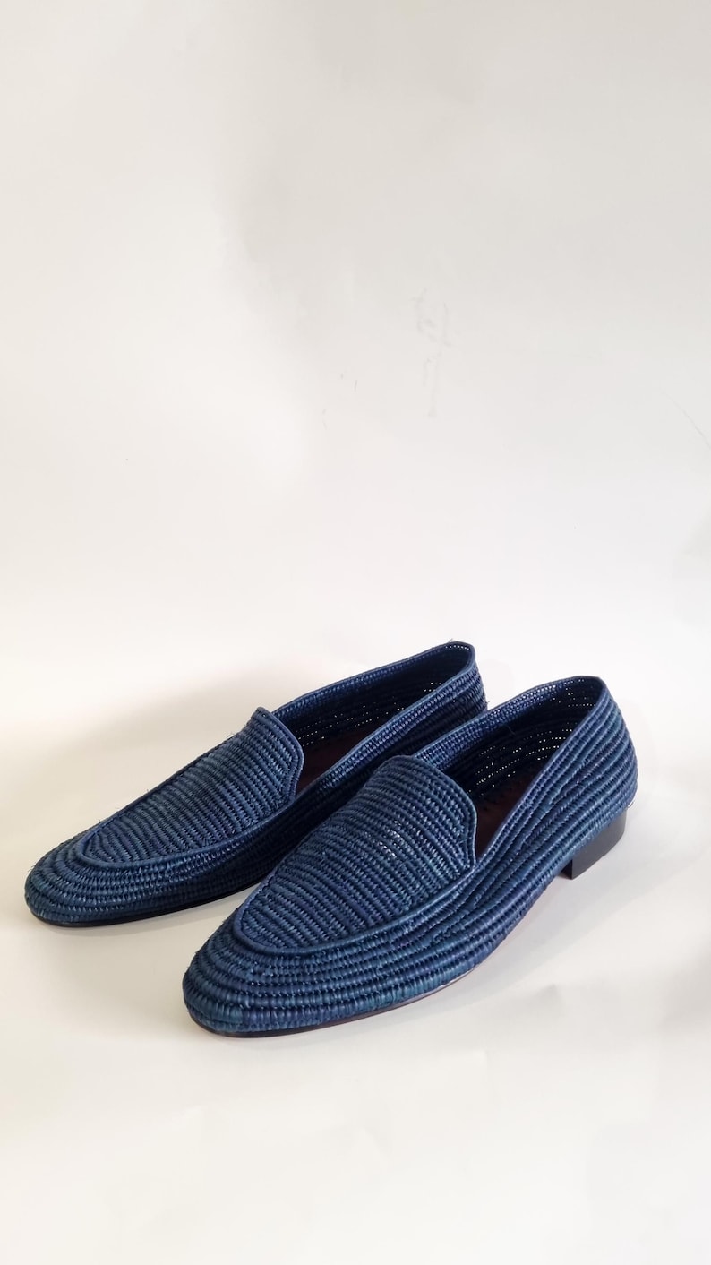 May include: A pair of blue woven leather loafers. The loafers have a pointed toe and a woven upper.