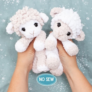 May include: Two plush sheep toys made of soft, chunky yarn. One sheep is light beige with a white face, and the other is white with a light beige face. Both have large black safety eyes and embroidered noses. A blue oval label reads NO SEW.
