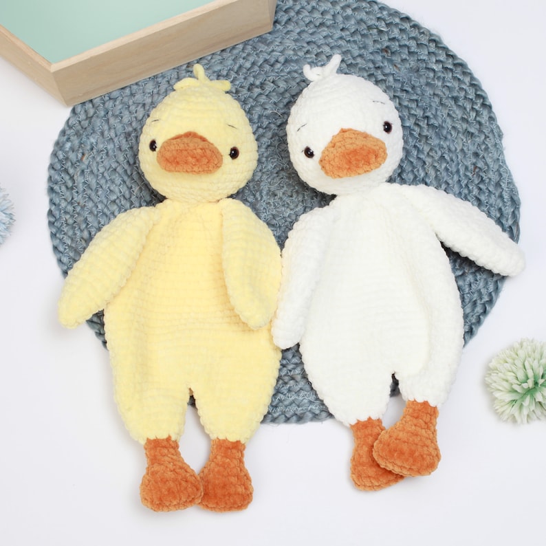 May include: Two crocheted stuffed duck toys. One is yellow and the other is white. Both have orange beaks and feet.