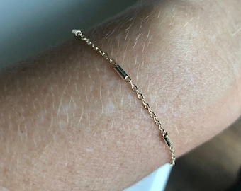 Puede incluir: Un delicado brazalete de cadena dorada con pequeños eslabones rectangulares.