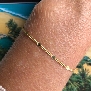 Puede incluir: Una delicada pulsera dorada con peque&ntilde;os abalorios redondos y un dise&ntilde;o de cadena. La pulsera se lleva en la mu&ntilde;eca, mostrando su simple elegancia. La pulsera mide aproximadamente 17,78 cm de largo.