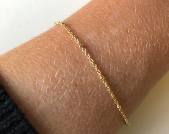 Puede incluir: Un delicado brazalete de cadena dorada con pequeñas cuentas redondas.