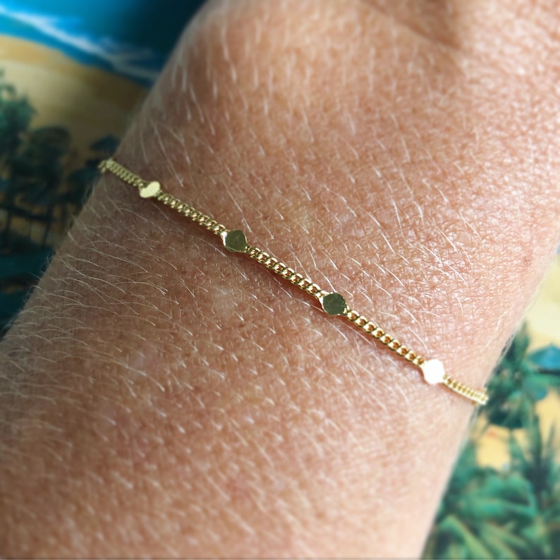 Puede incluir: Una delicada pulsera dorada con una fina cadena y peque&ntilde;os abalorios circulares espaciados. La pulsera es una joya sencilla y elegante, perfecta para el uso diario. La pulsera mide aproximadamente 17,8 cm de largo.