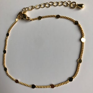 Puede incluir: Una delicada tobillera dorada con dise&ntilde;o de cadena. La tobillera presenta peque&ntilde;os acentos redondos dorados espaciados uniformemente a lo largo de la cadena. Tiene un cierre de mosquet&oacute;n y una cadena ajustable.