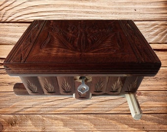May include: A wooden puzzle box with a carved floral design on the lid. The box has a sliding mechanism and a small keyhole.