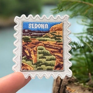 May include: White embroidered patch with a red, orange, and green landscape scene and the word "SEDONA" in blue lettering. The patch is shaped like a postage stamp.