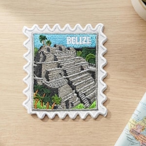 Può includere: Una toppa ricamata quadrata con bordo smerlato che raffigura una piramide maya in Belize. Il design include un cielo azzurro, alberi verdi e gradini in pietra grigia. La parola BELIZE è ricamata in bianco nella parte superiore.
