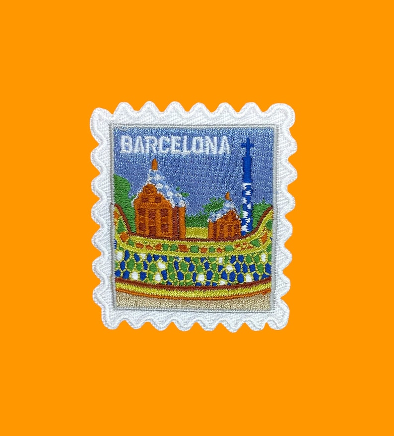 Pu&ograve; includere: Toppa ricamata bianca con un designo blu, verde e arancione di un edificio con la parola "BARCELONA" sopra.