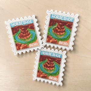May include: Three rectangular embroidered patches shaped like postage stamps with scalloped edges. Each patch features a landscape illustration of Horseshoe Bend with a winding blue river, red rock formations, and the text HORSESHOE BEND.
