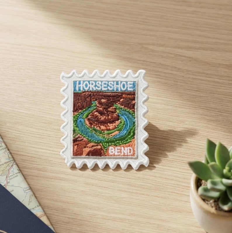 May include: A rectangular embroidered patch shaped like a postage stamp featuring a landscape of Horseshoe Bend. The design includes brown rock formations, a winding blue river, and green vegetation. The text HORSESHOE BEND is stitched in white.