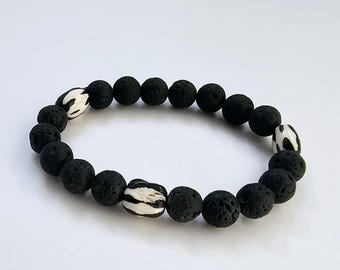 May include: A black lava rock bracelet with two white and black patterned beads.