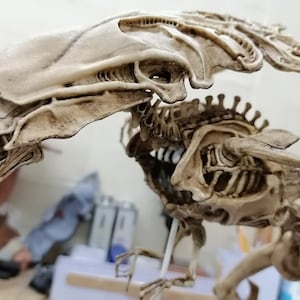 Puede incluir: Modelo beige de una criatura alienígena, con estructura esquelética y cresta distintiva. El modelo destaca el intrincado diseño de la criatura, incluyendo extremidades alargadas y una detallada representación de su anatomía.