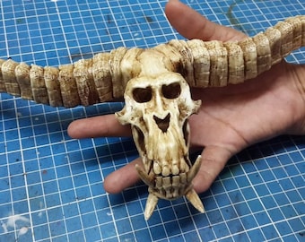 May include: A detailed, hand-painted, bone-colored skull with large horns. The skull has a toothy grin and is made of a textured material.