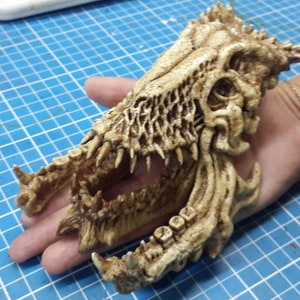 May include: A detailed, beige, bone-like sculpture of a creature's skull with sharp teeth and intricate bone patterns.